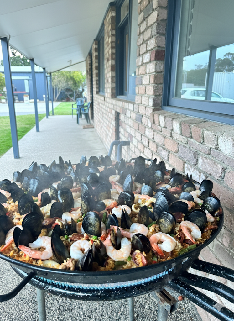 Chef cooking paella outdoors at an event